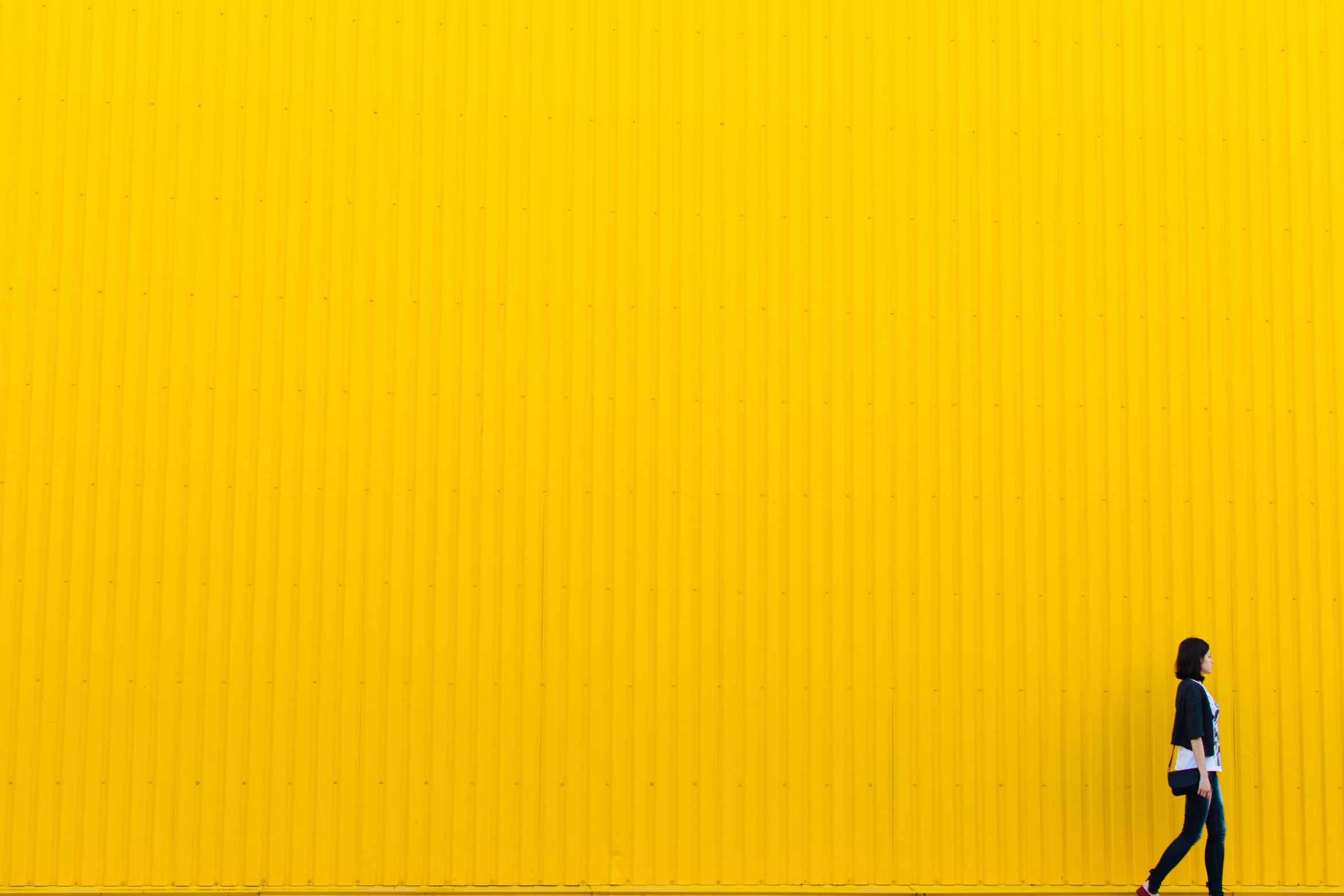 Woman Standing Beside Yellow Paint Wall